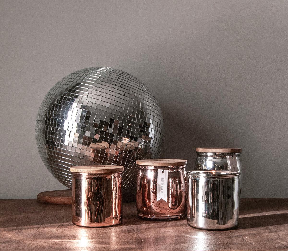 disco ball with metallic colored candles on wooden table